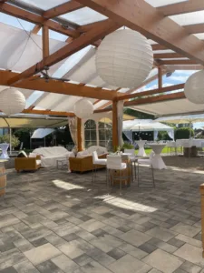 Überdachter Außenbereich im Sängerhof Rheinau mit Lounge-Möbeln, Stehtischen und Dekoration für Hochzeiten.