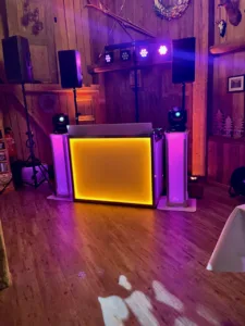 DJ-Setup mit leuchtender Front und Lichttechnik in rustikaler Hochzeitslocation in Freiamt Hoch