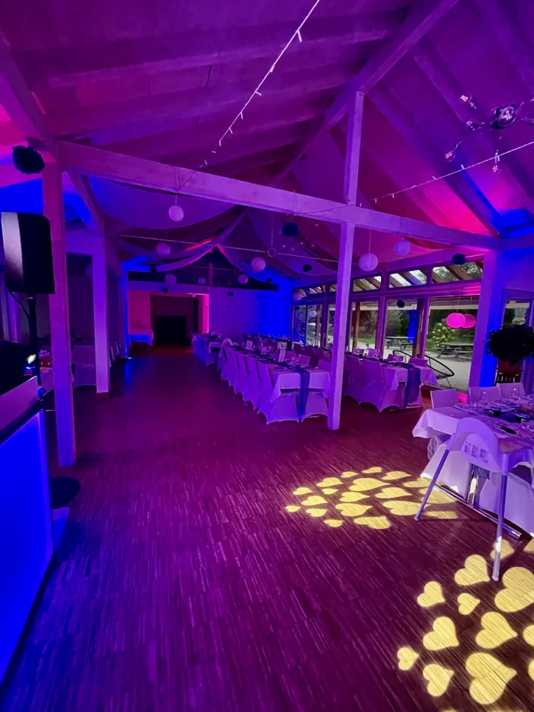 Festsaal im Haus am Teich bei einer Hochzeit mit stimmungsvoller Ambientebeleuchtung in Pink und Blau sowie Herzprojektionen auf dem Boden.