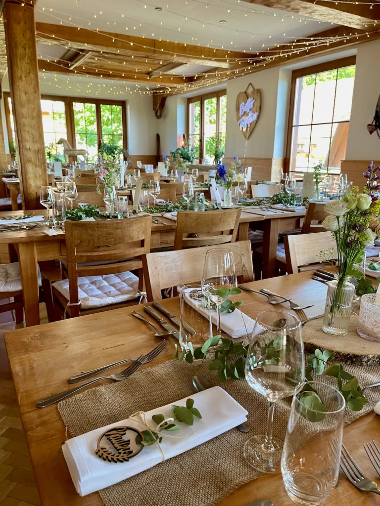 Hochzeit im Nillhof Fischerbach: Rustikal dekorierte Holztische mit Blumenschmuck, Lichterketten und festlicher Tischdekoration.